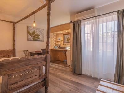 Helles Hotelzimmer mit Holzbetten, Schreibtisch und großen Fenstern mit Vorhängen.