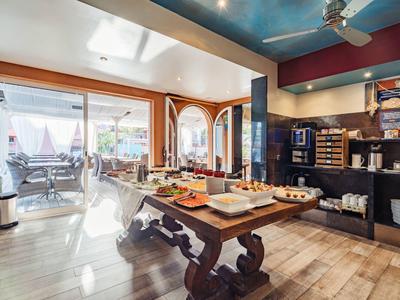 Rustikaler Frühstückstisch im Hotel mit Auswahl an Speisen und Blick auf Terrasse.