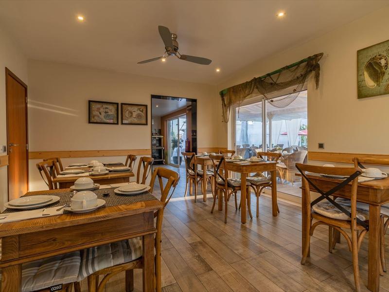 Gemütlicher Speiseraum mit Holztischen und Stühlen, gedeckt für mehrere Gäste.