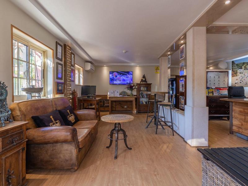 Gemütlicher Hotel-Lounge-Bereich mit Ledersofas, Holzmöbeln und Fernseher an der Wand.