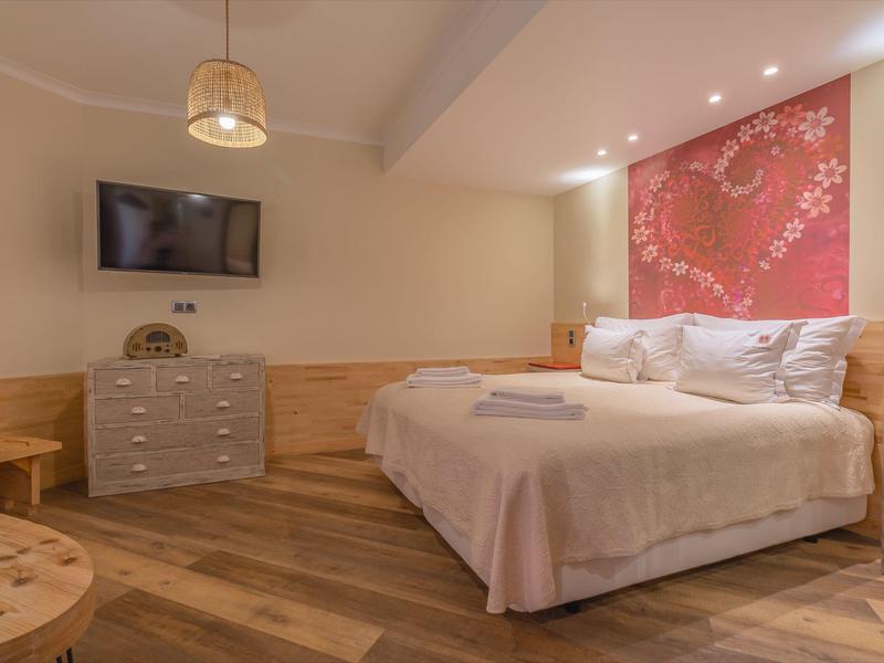 Gemütliches Hotelzimmer mit Doppelbett, Holzmöbeln und Wandfernseher.