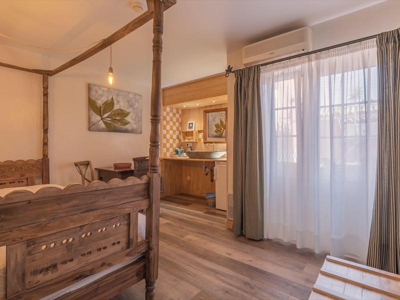 Helles Hotelzimmer mit Holzbetten, Schreibtisch und großen Fenstern mit Vorhängen.