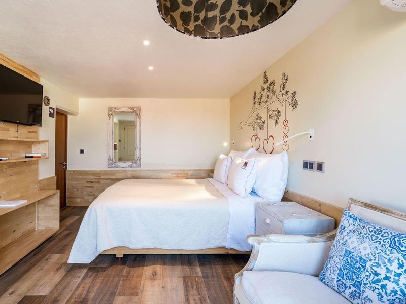 Helles Hotelzimmer mit Doppelbett, Fernseher, Stuhl und Holzboden.