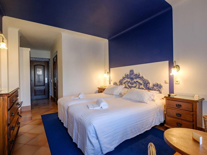 Geräumiges Schlafzimmer mit blauer Wand, großem Bett, Holzmöbeln und warmem Licht.