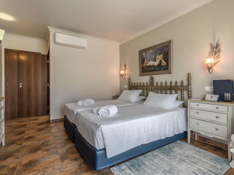 Modernes Schlafzimmer mit großem Bett, weißen Möbeln, wandhängender Klimaanlage und Parkettboden.