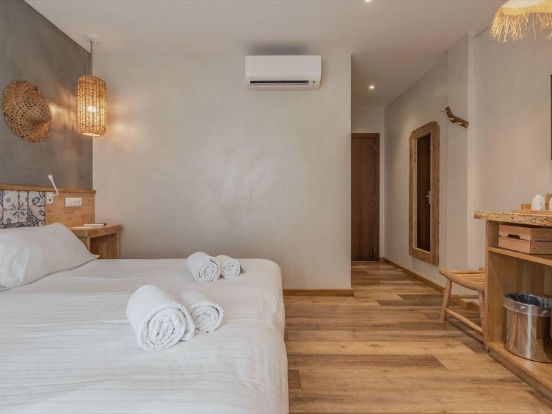 Modernes, gemütliches Schlafzimmer mit Doppelbett, Holzfußboden, TV und Klimaanlage.