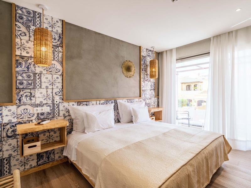 Modernes Schlafzimmer mit Doppelbett, Holzmöbeln, gemusterten Wandfliesen und großen Fenstern.