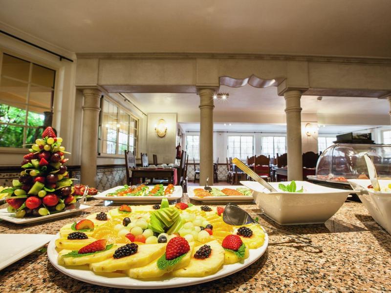 Buffet mit Teller voller Canapés, Obstplatte und Salaten auf Marmorarbeitsfläche in hellem Raum.