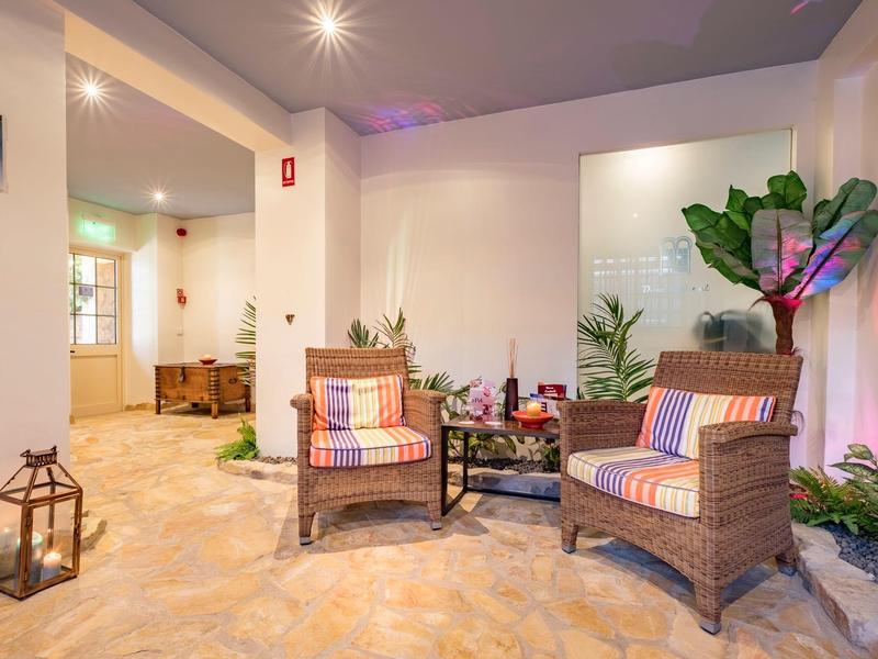 Gemütliche Sitzecke mit zwei Korbstühlen, Kissen, Pflanzen und Laterne auf hellem Boden.