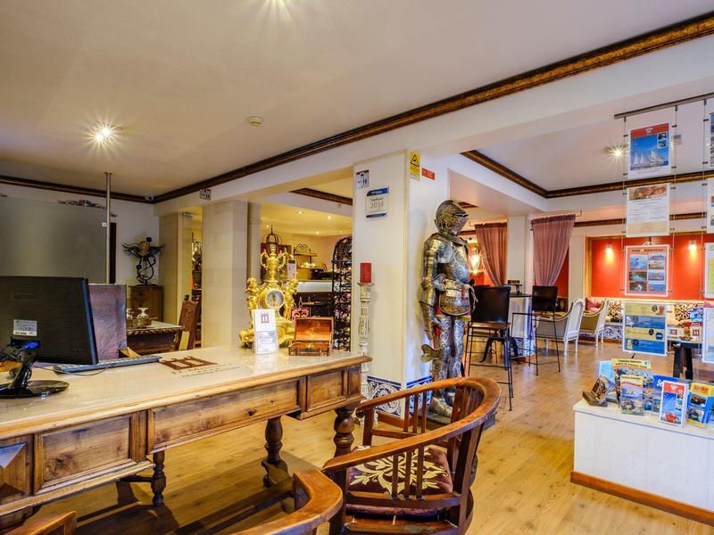 Innenraum einer historischen Bibliothek mit antiken Möbeln, beleuchteten Regalen und Ritterrüstung.