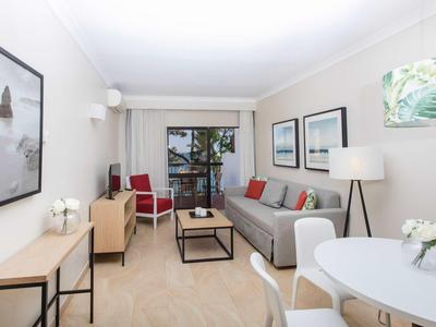 Helles Wohnzimmer mit grauem Sofa, roten Stühlen, Holz- und Metallmöbeln, modernen Wandbildern und großem Fenster.