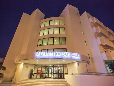 Modernes Hotelgebäude mit dem Schriftzug "Albufeira Sol" bei Nacht, beleuchteter Eingangsbereich.
