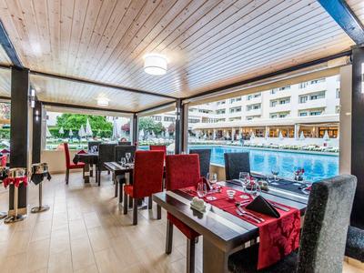 Gemütlicher Wellnessraum mit blauen Whirlpool, dunklen Holzwänden und entspannenden Sesseln.