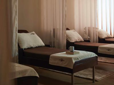 Dunkelbraune Liegen mit weißen Handtüchern und Kissen in einem schwach beleuchteten Raum.