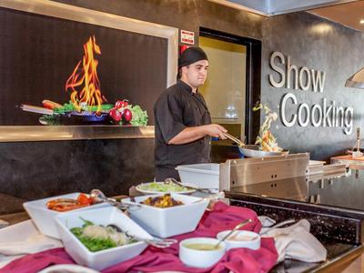 Koch bereitet vor Buffet mit frischem Gemüse und Gewürzen in Show-Kochbereich zu.