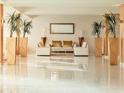 Heller Raum mit glänzendem Marmorfußboden, Sofa, Couchtisch und hohen Zimmerpflanzen.