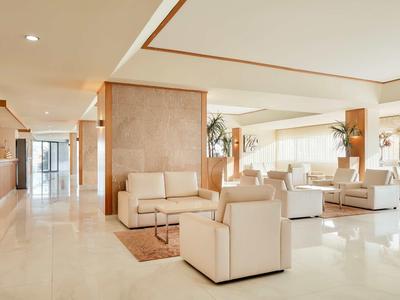 Helle, moderne Lobby mit cremefarbenen Sofas, Polstern und großen Fenstern für viel Tageslicht.
