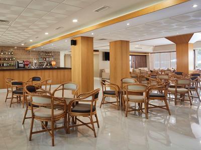 Großer heller Gastraum mit Holzmöbeln und langer Bar auf der linken Seite.