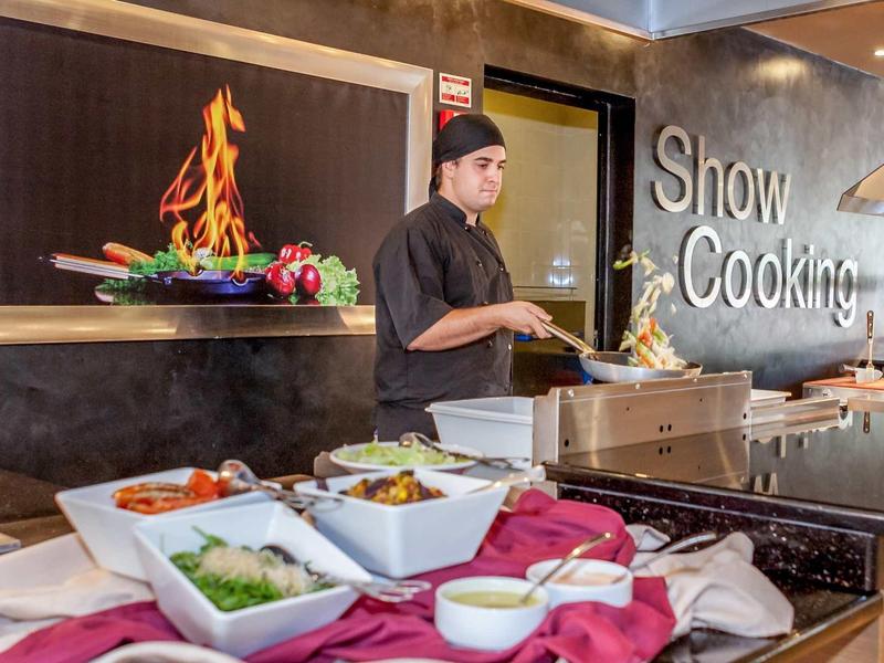 Koch bereitet vor Buffet mit frischem Gemüse und Gewürzen in Show-Kochbereich zu.