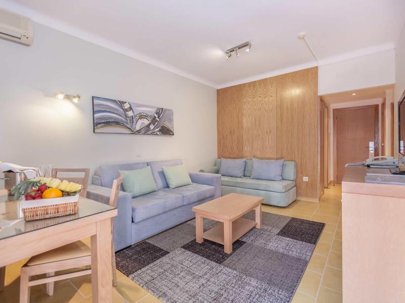 Helles Wohnzimmer mit zwei blauen Sofas, Holztisch, Teppich und Bild an der Wand.