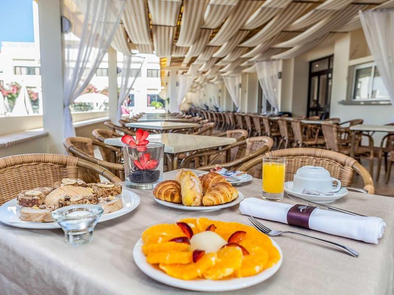 Gemütliches Frühstück mit frischem Obst, Croissants, Gebäck, Saft und Kaffee auf gedecktem Tisch.