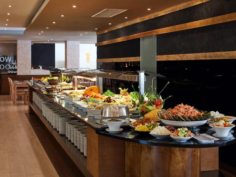 Großes Buffet mit vielfältigen Speisen, frischem Obst und Salaten in modernem Restaurant.