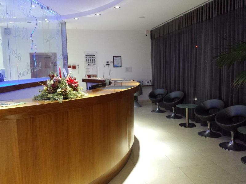 Eleganter Empfangstresen mit Blumenarrangement und Sitzreihe aus schwarzen Stühlen im Wartebereich.