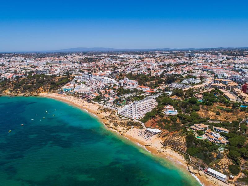 Luftaufnahme einer Küstenstadt mit strahlend blauem Meer, Sandstrand und dicht bebauten Gebieten.