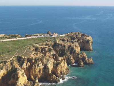 Klippenlinie mit markanten Felsformationen an türkisblauem Meer unter blauem Himmel.