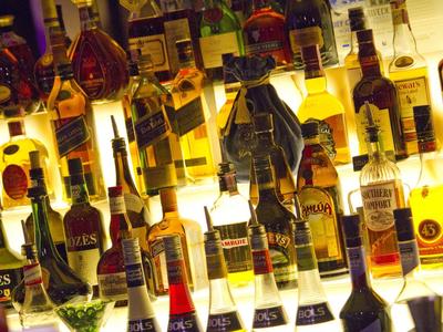 Verschiedene Whisky- und Spirituosenflaschen stehen dicht nebeneinander auf einem beleuchteten Regal.