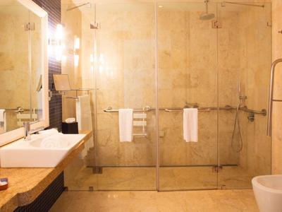 Modernes Badezimmer mit großer Glaskabine, Doppelwaschbecken und warmem, beigem Farbton.