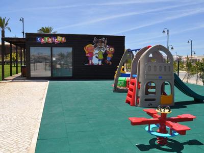 Kinderspielplatz mit Rutsche, Wippe, Klettergerüst und Gebäude mit bunter Wandgestaltung.