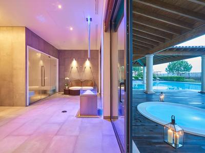 Moderner Innen- und Außenbereich mit Whirlpool, Glaswand, warmen Lichtakzenten und Holzdecke.