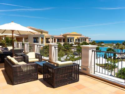 Luxuriöse Terrasse mit bequemen Sitzmöbeln, Sonnenschirmen und Blick auf Pool und Meer.