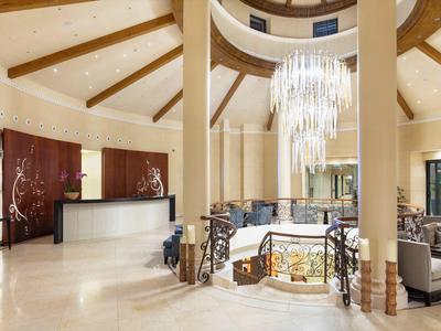 Großer Empfangsbereich mit heller Marmorfläche, Kronleuchter und moderner Sitzgruppe im edlen Design.