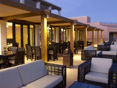 Moderne Terrasse mit Sitzgruppen aus Sofas und Stühlen bei Abendlicht, warme Beleuchtung innen.