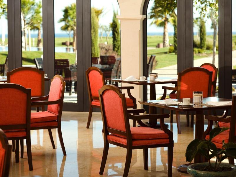 Ein heller, eleganter Essbereich mit roten Polsterstühlen und großer Fensterfront zum Garten.