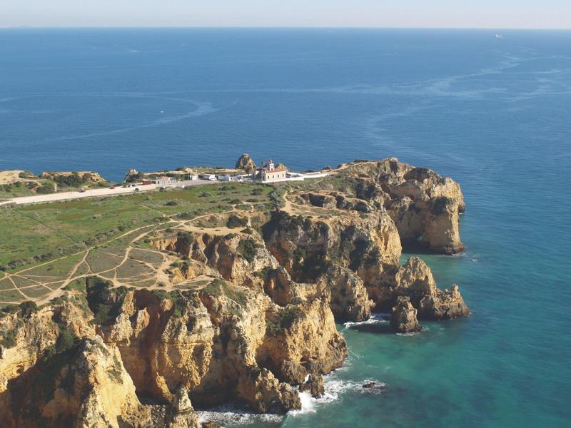 Klippenlinie mit markanten Felsformationen an türkisblauem Meer unter blauem Himmel.