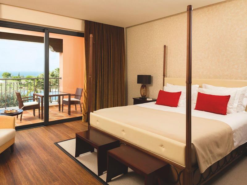 Modernes Hotelzimmer mit Doppelbett, Holzfußboden, Balkon und gemütlichen Sitzmöbeln.