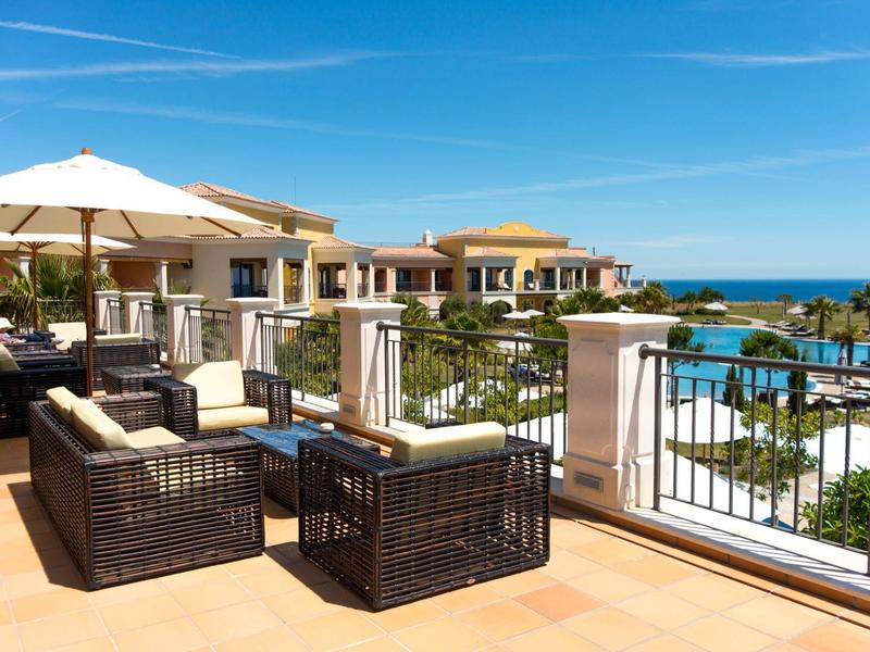 Luxuriöse Terrasse mit bequemen Sitzmöbeln, Sonnenschirmen und Blick auf Pool und Meer.