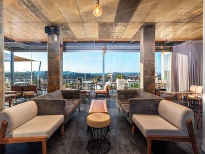 Modern eingerichteter Lounge-Bereich mit Holzdecke, Ledersofas und großflächigen Fenstern.