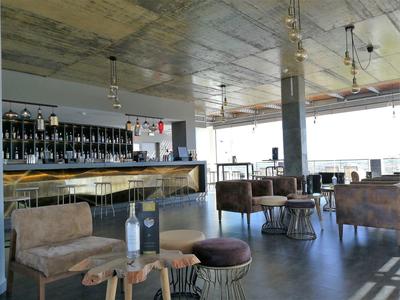 Moderner Barbereich mit braunen Sesseln, Holztheke und großen Fenstern für viel Tageslicht.