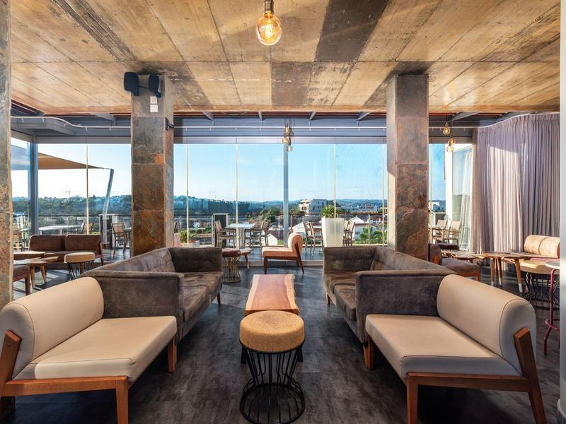 Modern eingerichteter Lounge-Bereich mit Holzdecke, Ledersofas und großflächigen Fenstern.