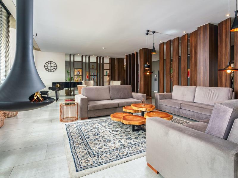 Modernes Wohnzimmer mit zwei grauen Sofas, hängendem Kamin und Holzwand mit eingebauten Regalen.