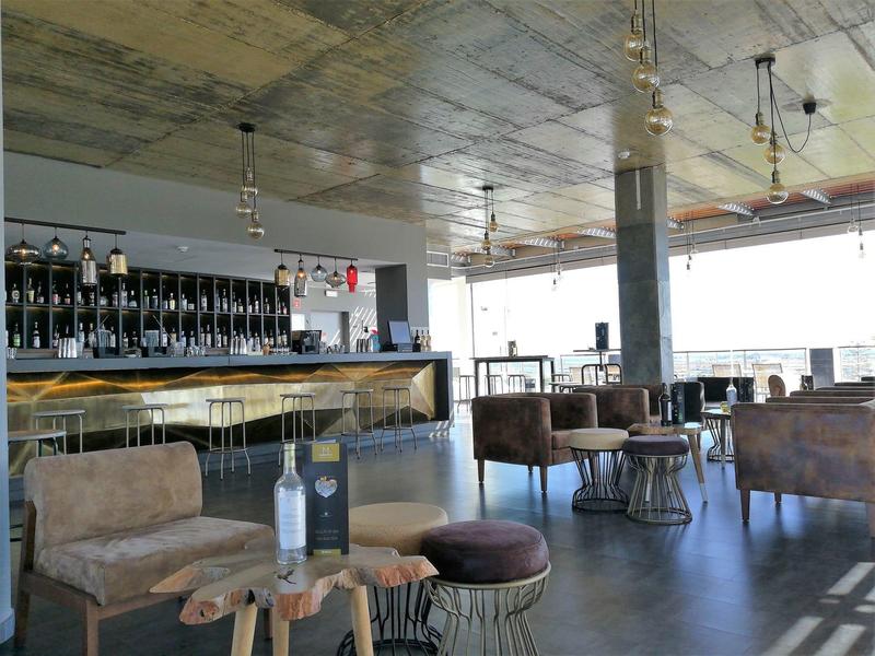 Moderner Barbereich mit braunen Sesseln, Holztheke und großen Fenstern für viel Tageslicht.