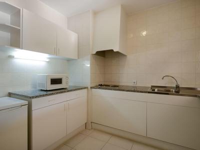 Moderne weiße Küche mit Herd, Spüle, Mikrowelle und schlichten Schränken in U-Form.