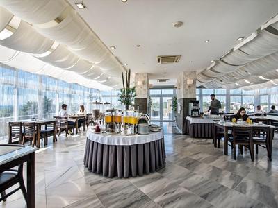 Großer heller Gastraum mit Tischen, Stühlen und einer zentralen Getränkestation.