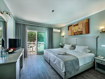 Helles Hotelzimmer mit Doppelbett, Balkon, Schreibtisch, Klimaanlage und moderner Wanddekoration.