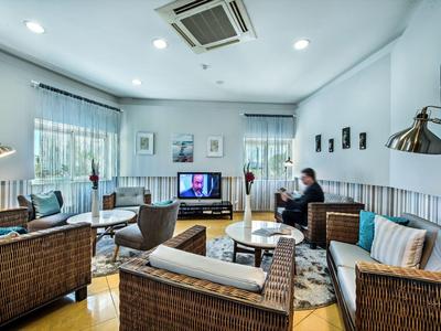 Moderne, helle Lounge mit Korbsesseln, Holzboden, mehreren Sitzgruppen und großer Klimaanlage.