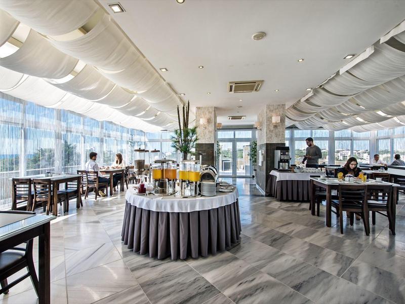 Großer heller Gastraum mit Tischen, Stühlen und einer zentralen Getränkestation.